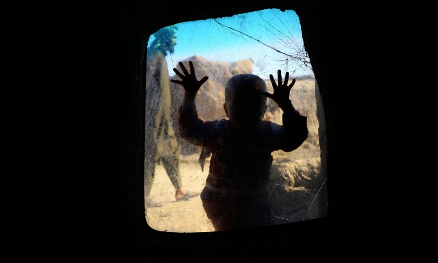 TOPSHOT - In this photograph taken on May 21, 2018 an internally displaced Afghan child looks on from a windows in her temporary home at a refugee camp on the outskirts of Herat.  AFP PHOTO  HOSHANG HASHIMI